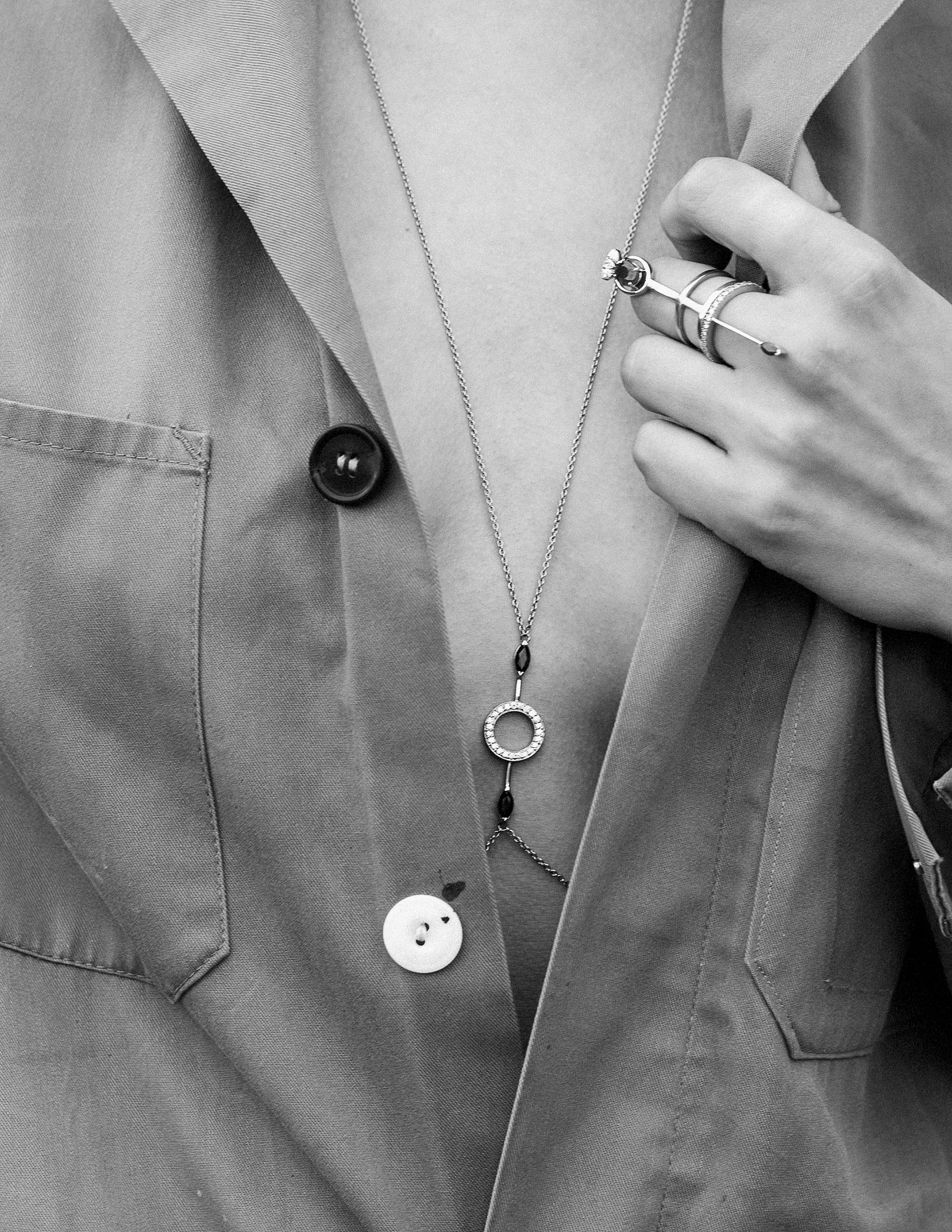 Close up black and white shot of a girl wearing a simple gold necklace and matching ring