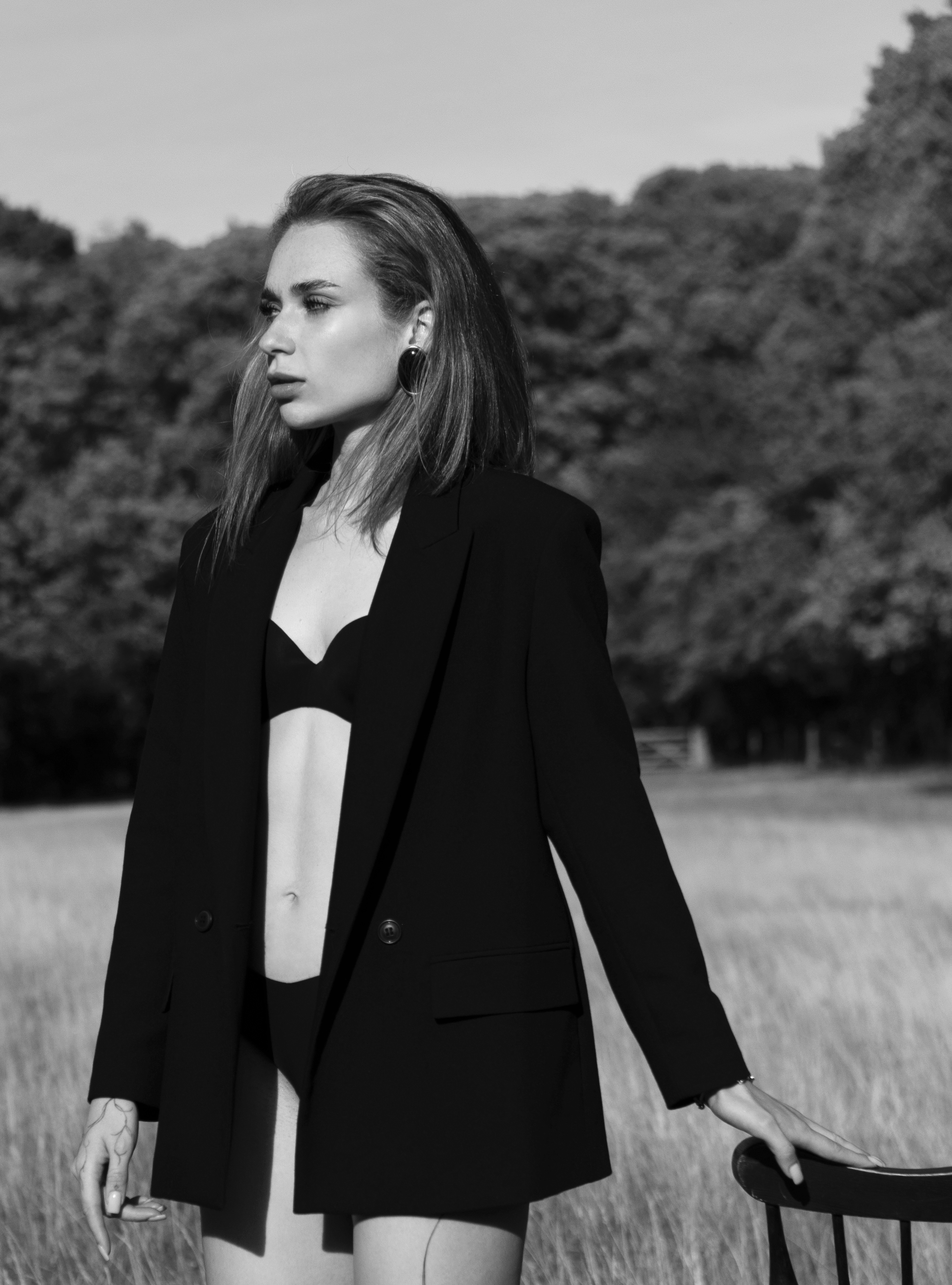 A girl stands in a field wearing a black blazer